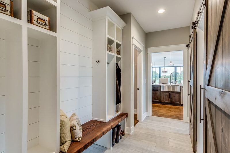 Finished mudroom with white trim, built-in lockers, a bench and shiplap walls