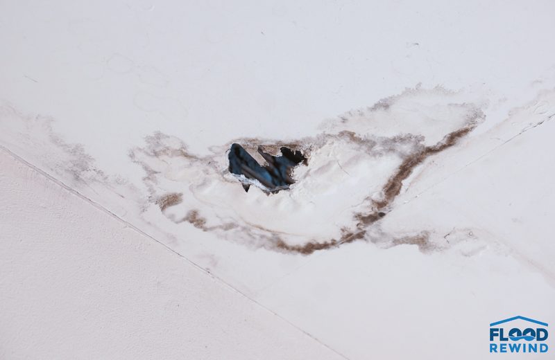 Water-stained ceiling drywall with a hole where the wet board gave way