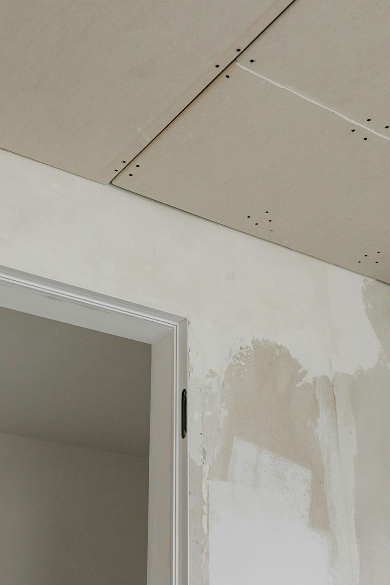 New drywall with finished joint compound around a door frame and ceiling