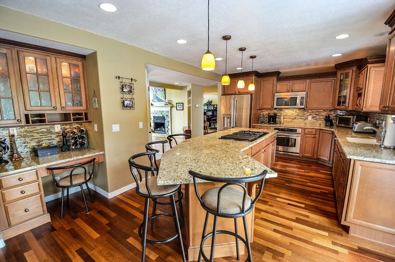 Kitchen with wood cabinets, an island with bar stools and hardwood floors