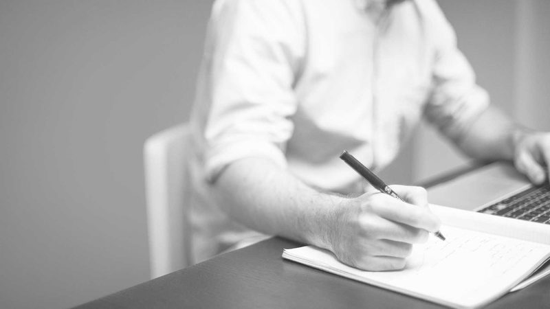 Person writing notes on paperwork at a table